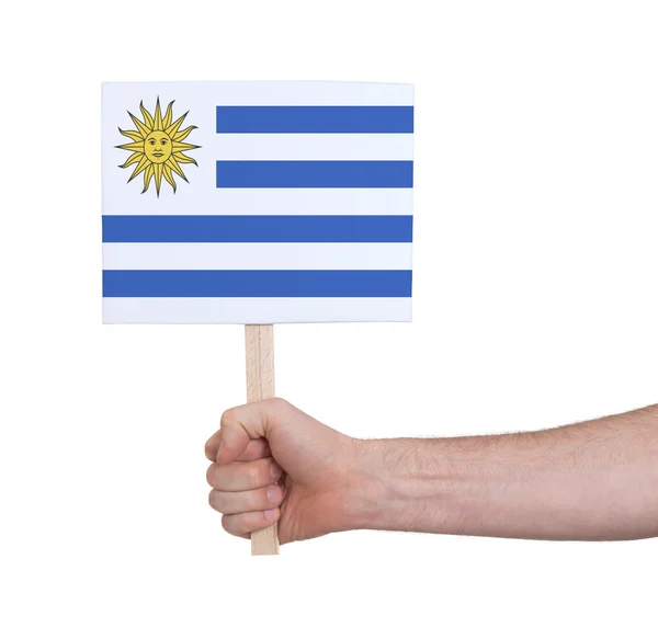 Mão segurando cartão pequeno - Bandeira do Uruguai — Fotografia de Stock