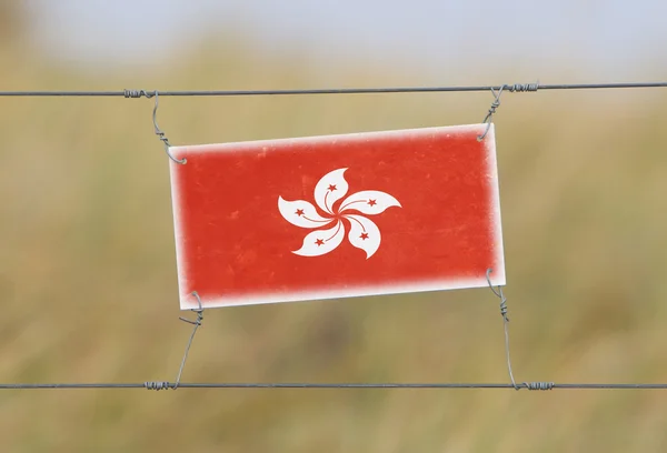 Clôture frontalière - Vieux panneau en plastique avec un drapeau — Photo