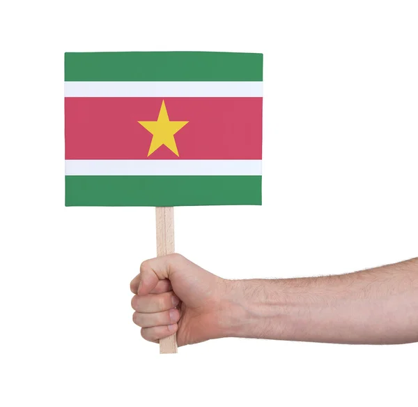 Mão segurando cartão pequeno - Bandeira do Suriname — Fotografia de Stock