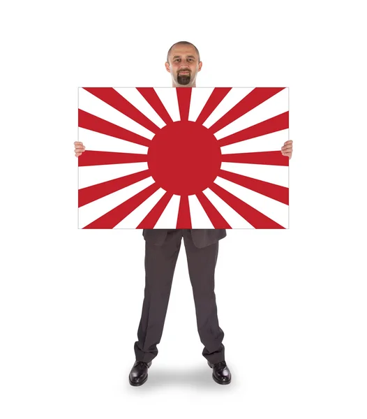 Un hombre de negocios sonriente sosteniendo una gran tarjeta, bandera de Japón —  Fotos de Stock