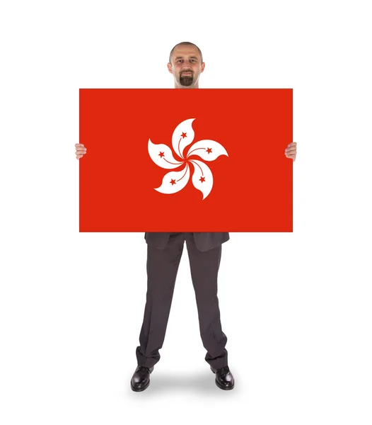 Un hombre de negocios sonriente sosteniendo una tarjeta grande, bandera de Hong Kong —  Fotos de Stock