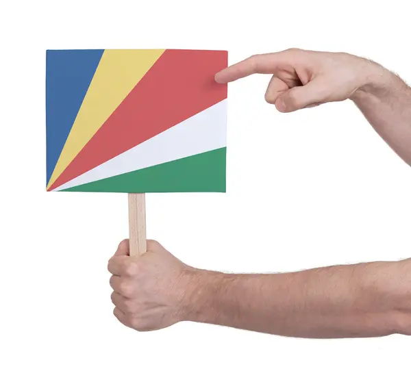 Mano sosteniendo una tarjeta pequeña - Bandera de Seychelles — Foto de Stock