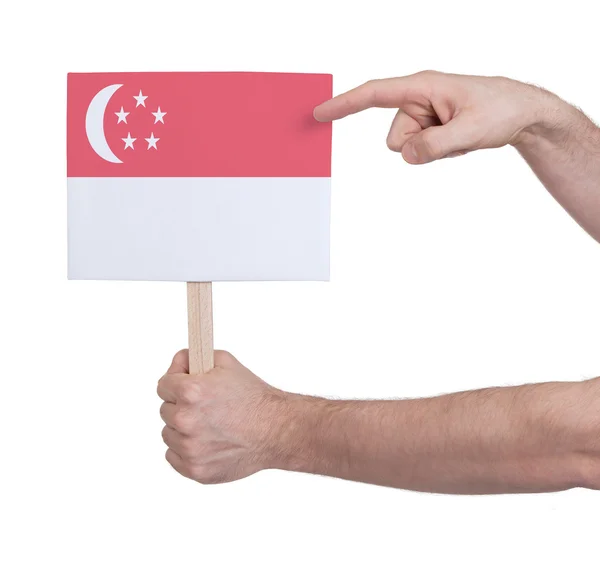 Mão segurando cartão pequeno - Bandeira de Singapura — Fotografia de Stock