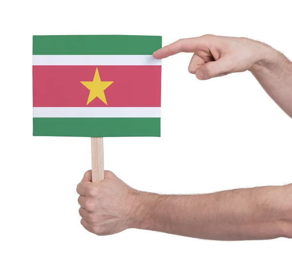 Mano sosteniendo una tarjeta pequeña - Bandera de Surinam — Foto de Stock