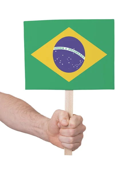 Mão segurando cartão pequeno - Bandeira do Brasil — Fotografia de Stock