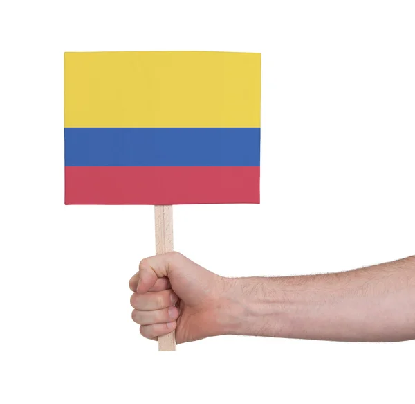 Hand som håller litet kort - flagga i Colombia — Stockfoto