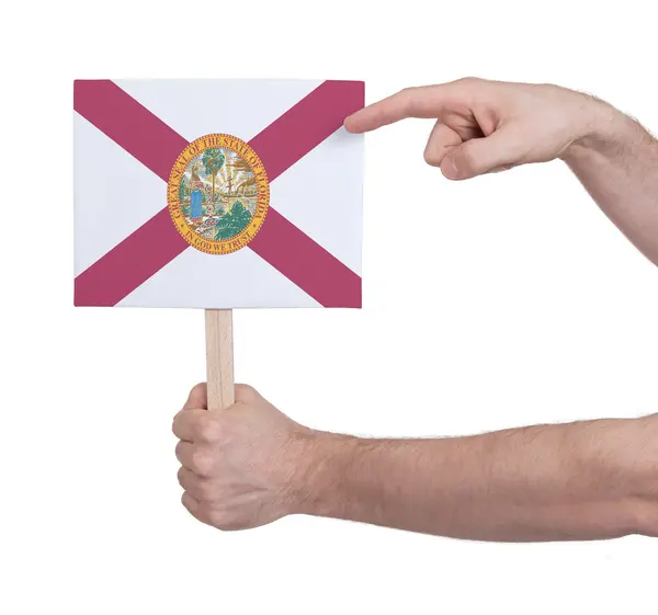 Mano sosteniendo una tarjeta pequeña - Bandera de Florida —  Fotos de Stock