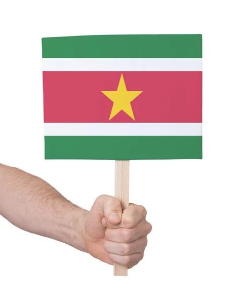 Mano sosteniendo una tarjeta pequeña - Bandera de Surinam — Foto de Stock