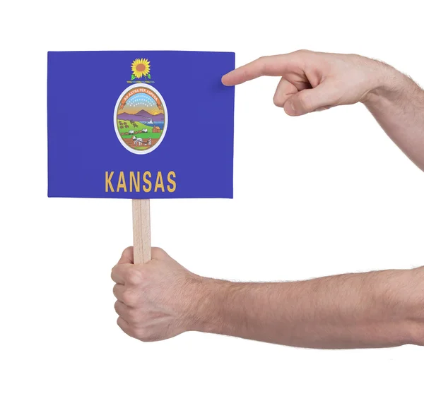 Mano sosteniendo una tarjeta pequeña - Bandera de Kansas —  Fotos de Stock