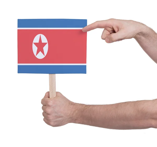 Mano sosteniendo una tarjeta pequeña - Bandera de Corea del Norte —  Fotos de Stock