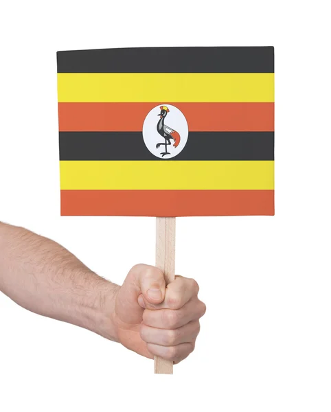 Mão segurando cartão pequeno - Bandeira de Uganda — Fotografia de Stock