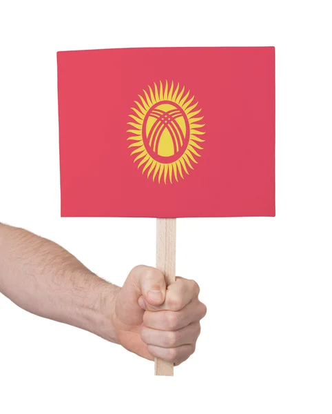 Mano che tiene la piccola carta - Bandiera del Kirghizistan — Foto Stock