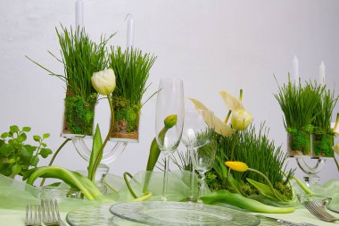 Çiçeklerle, mumlarla, beyaz arka planda çimlerle dolu bir hayat.