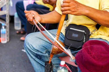 Chiang Mai caddesinde Tayland kemanı çalan Tayland sokak müzisyeninin yakın çekimi. Tayland kemanı, telli enstrümanlarda orkestra şefi olarak kullanılır ve referans melodisi için temelidir.