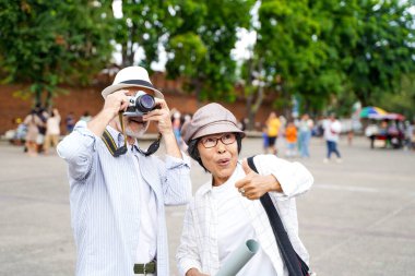 Yakın plan Amerikalı kıdemli turist ve karısı şehirde bulanık arka planda fotoğraf çekiyorlar. Kıdemli turist konsepti