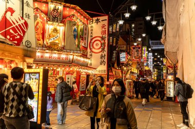 Osaka şehri, Japonya - 07 Aralık 2024: Shinsekai 'nin gece vakti insanlarla ve turistlerle yürüdüğü sokak manzarası. Shinsekai bölgesi, caddenin her iki tarafında da turistlerin en popüler olduğu dükkanlar ve restoranlarla dolu.