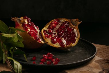 Nar ve açık nar karanlık bir masada bir tabakta.