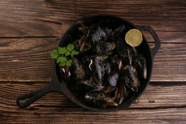 Tahta bir masada pişmeye hazır bir güveçte taze pişmiş midye.