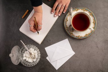 Koyu arkaplanda defter olan çay fincanı