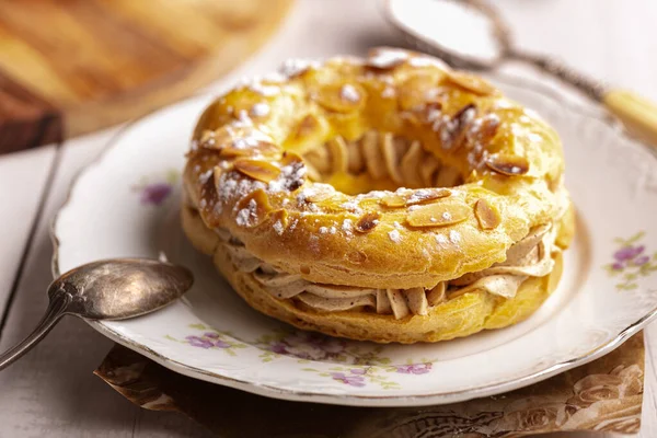 Beyaz ahşap bir masada eski bir tabakta küçük bir pasta Paris Brest