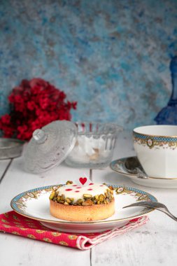 Tahta masada bir fincan çayla eski bir tabakta küçük bir turta.