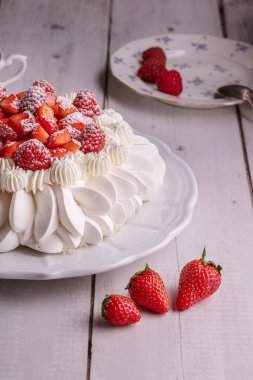  Ahşap bir masada bir fincan çayla kırmızı meyve pavlovası