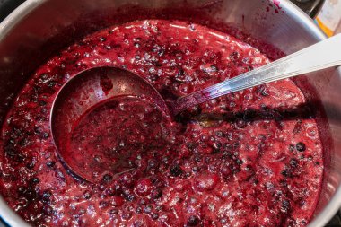 Kırmızı meyve reçeli bir tencerede pişiriliyor.