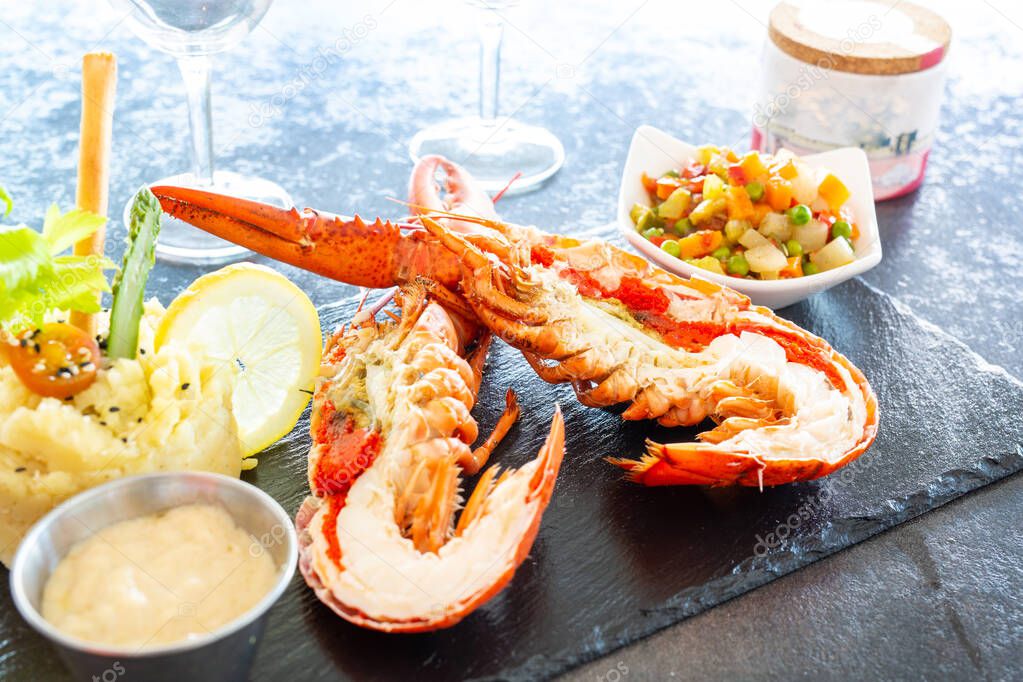 Lobster cut in half presented on a slate with vegetables