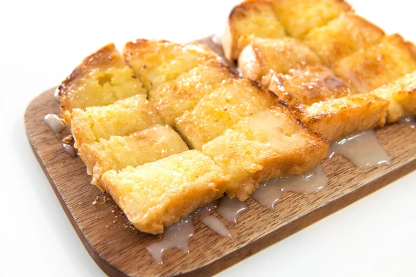 Bröd rostat bröd och kondenserad mjölk på träplatta — Stockfoto