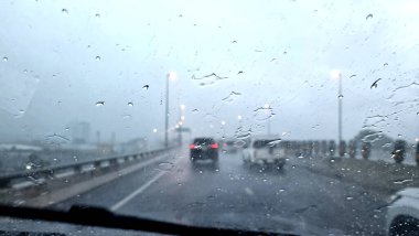 Otobanda yağmurlu bir akşamda ön cama yağmur damlaları düşer..