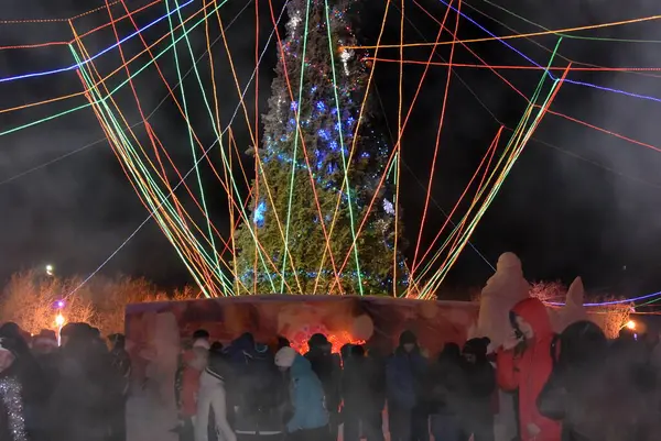 Karanlık bir gökyüzünün aydınlatması. Neon havai fişekler ve Noel ağacı.