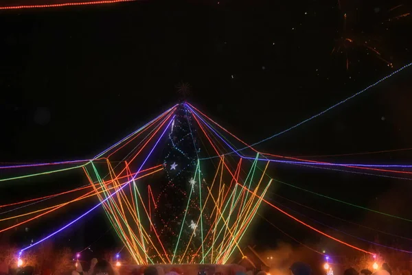 Karanlık bir gökyüzünün aydınlatması. Neon havai fişekler ve Noel ağacı.