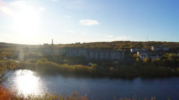 На північ від Росії покинуте село через річку на тлі сонця й осіннього листя. — стокове фото