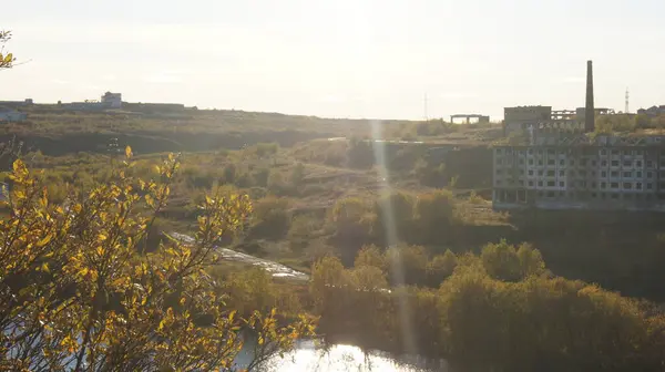 На північ від Росії покинуте село через річку на тлі сонця й осіннього листя. — стокове фото