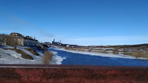 Der Frühling kommt in der nordrussischen Landschaft am Fluss und das alte Dorf am Hang schmilzt der Schnee — Stockfoto