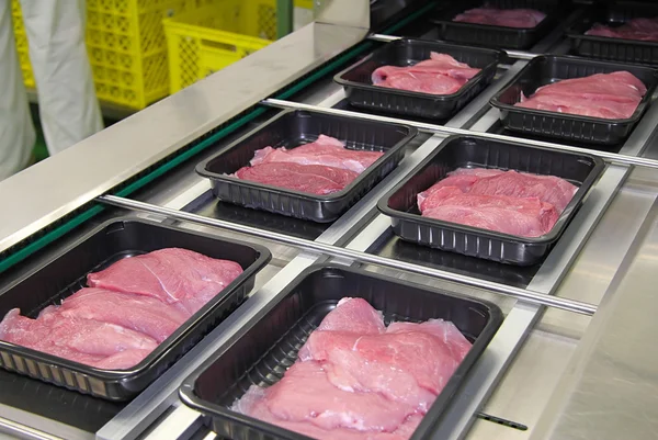 Packing of meat slices in boxes on a conveyor belt — Stock Photo, Image