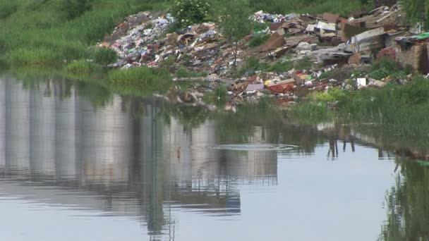 Выброс мусора на берегу реки — стоковое видео