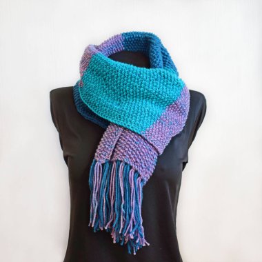 Ahşap bir arka planda mavi ve mor iplikten örülmüş eşarp..