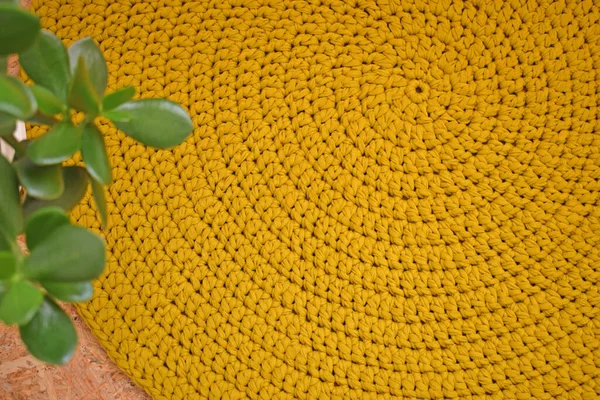Round knitted rug.Crocheting.Knitted mustard-colored background.