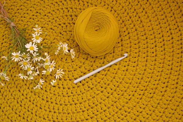 Round knitted rug.Crocheting.Knitted mustard-colored background.