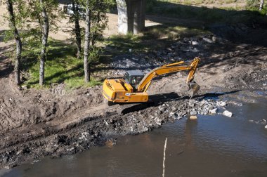 Backhoe working in a river clipart