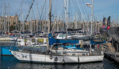 BARCELONA, İspanya - 7 Aralık 2023: yelkenliler ve yatlar eski Barcelona limanına yanaştı. Sahne, marinanın canlı atmosferini yakalıyor. Tekneler diziliyor ve arka planda binalar görülüyor.