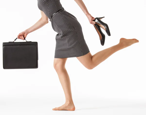 Business woman running and holding her shoes — стоковое фото