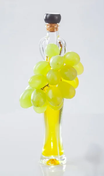 Bottiglia di olio di vite e grappolo di uva verde fresca — Foto Stock