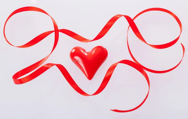 Στριμμένα κόκκινη κορδέλα και κεραμικά καρδιά — Φωτογραφία Αρχείου