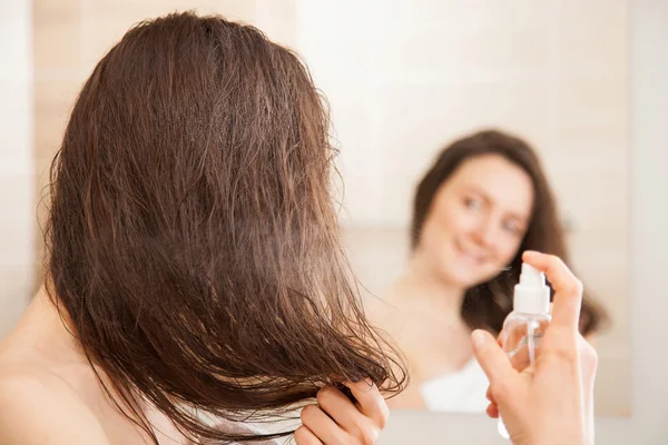 Mujer joven aplicando spray para el cabello — Foto de Stock