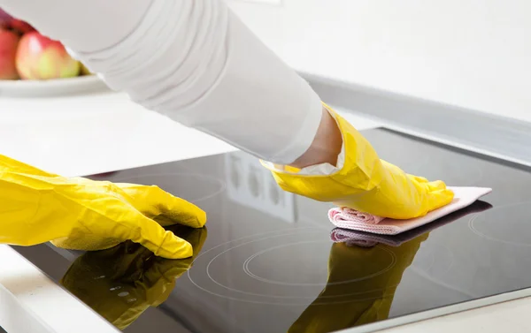 Housewife cleaning an induction plate — Stock Photo, Image