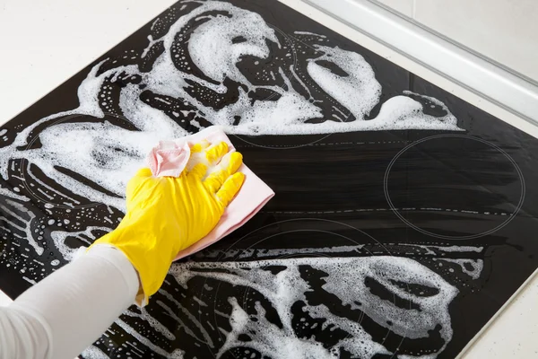 Housewife cleaning an induction plate — Stock Photo, Image