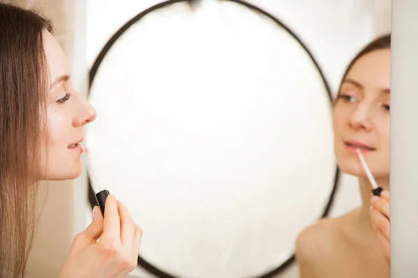 Beautiful young woman applying lipgloss — Stock Photo, Image