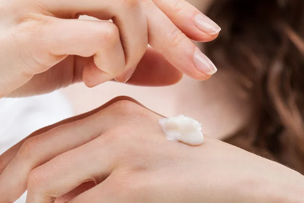 Mãos de mulher aplicando creme de mão — Fotografia de Stock